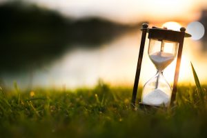 an hourglass is sitting in the grass at sunset
