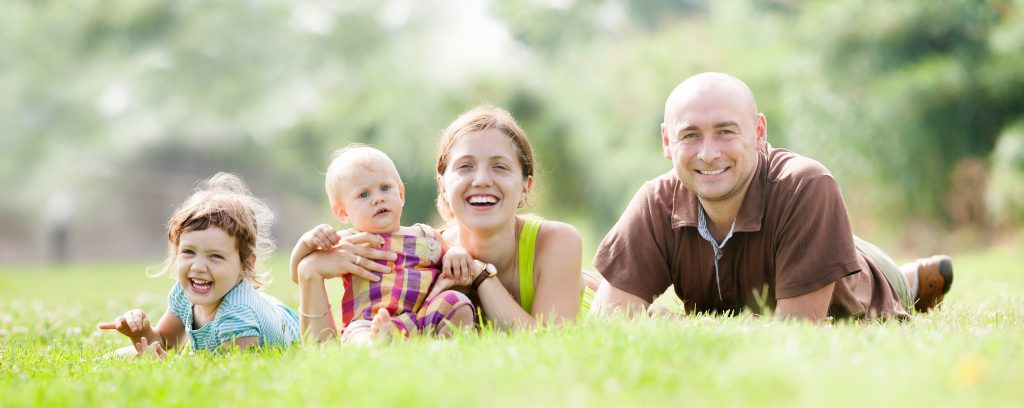 Family with two little girls laying on the grass